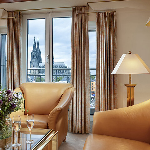  Elegant Heumarkt Suite at Maritim Hotel Cologne featuring comfortable leather chairs and a direct view of Cologne Cathedral.