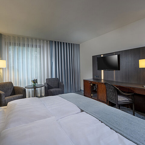 Modernly furnished Classic Smart room with desk, TV, seating area, and comfortable bed at Maritim Hotel Bremen.