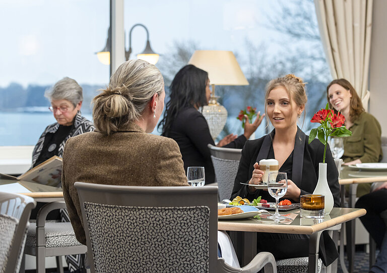 Restaurant Bellevue Guests in the Bellevue restaurant at the Maritim Hotel Kiel, relaxed conversation over drinks and food with a view of the sea.
