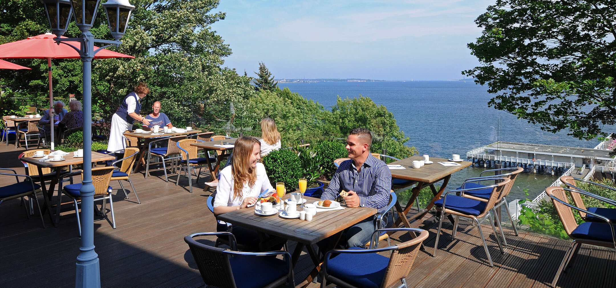 Panoramic terrace Panorama terrace at the Maritim Hotel Kiel with guests at breakfast, sunny weather and view of the fjord in the background.