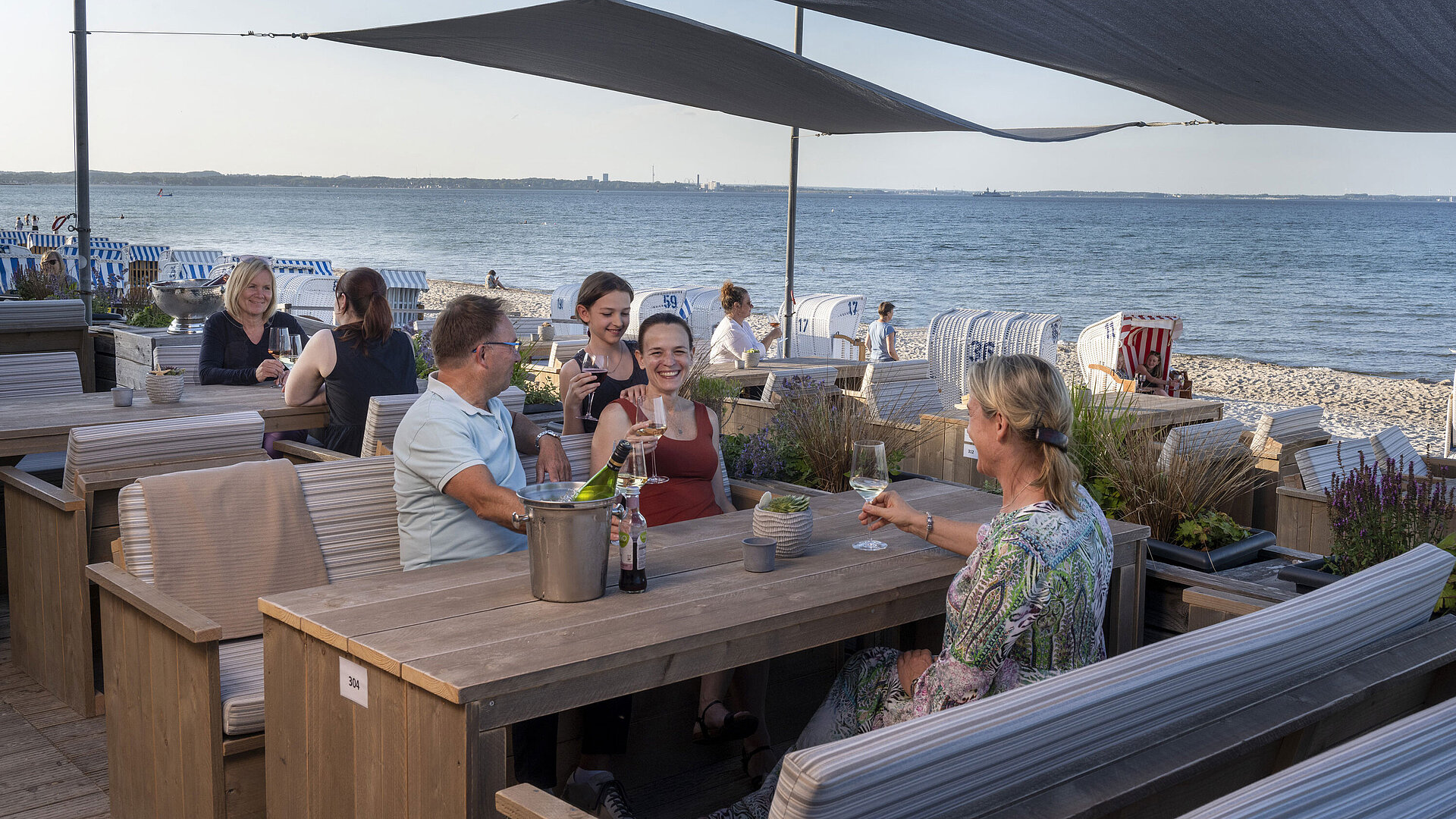 Beach Lounge Group of guests at the beach bar of Maritim Seehotel Timmendorfer Strand enjoying drinks with sea view and beach chairs.