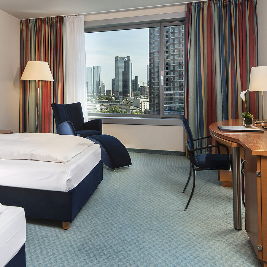 Comfort room Comfort room at Maritim Hotel Frankfurt with two single beds, desk, seating area, and skyline view.