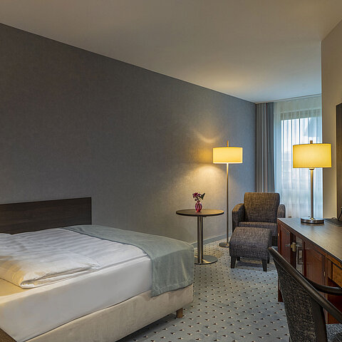 Modernly furnished Classic room with desk, TV, seating area, and comfortable bed at Maritim Hotel Bremen.